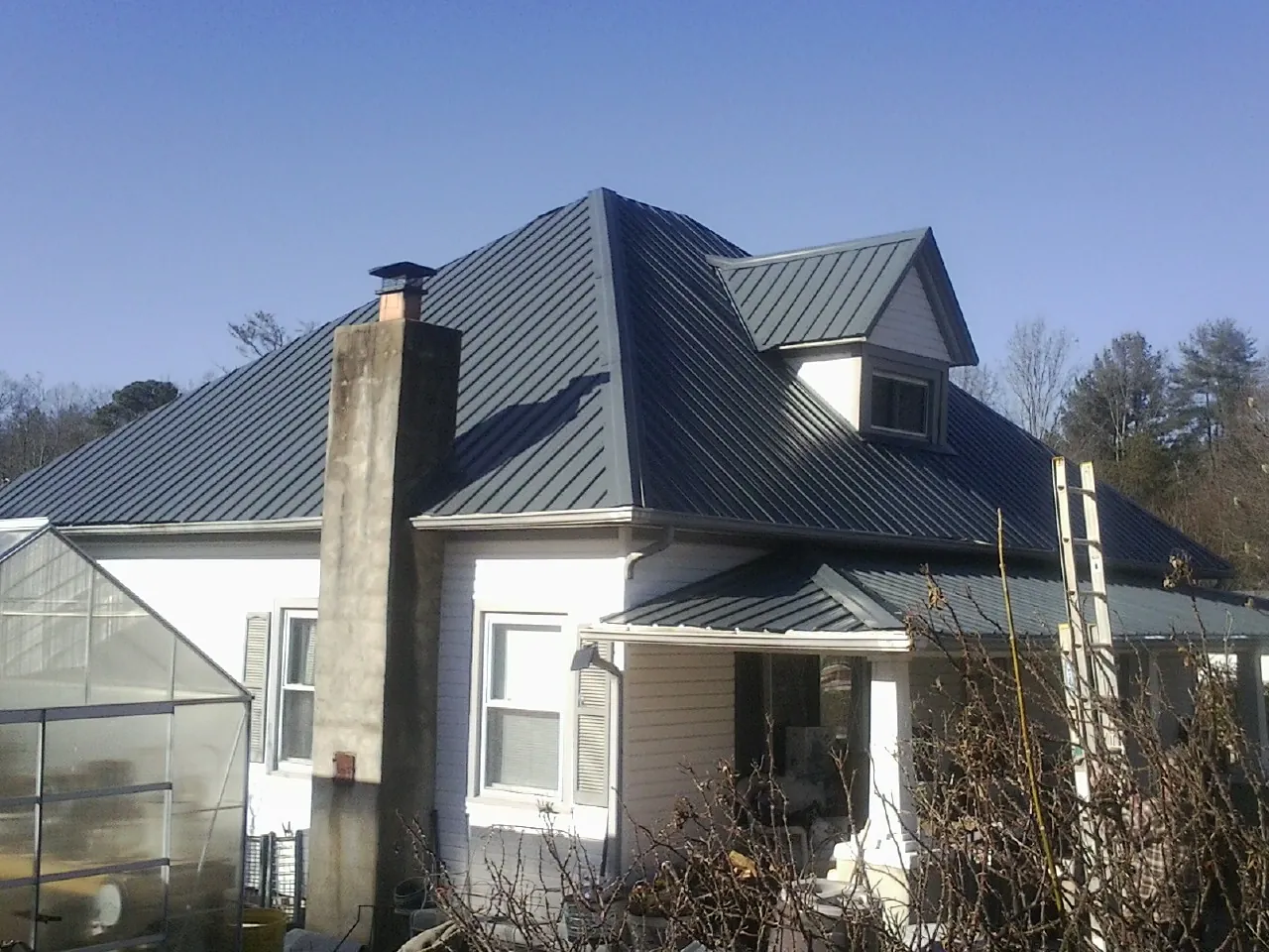 Dark blue standing seam metal roof on a white farmhouse with dormer — Slate & Tile Roof Repair by Roofing Brothers in Cave Creek