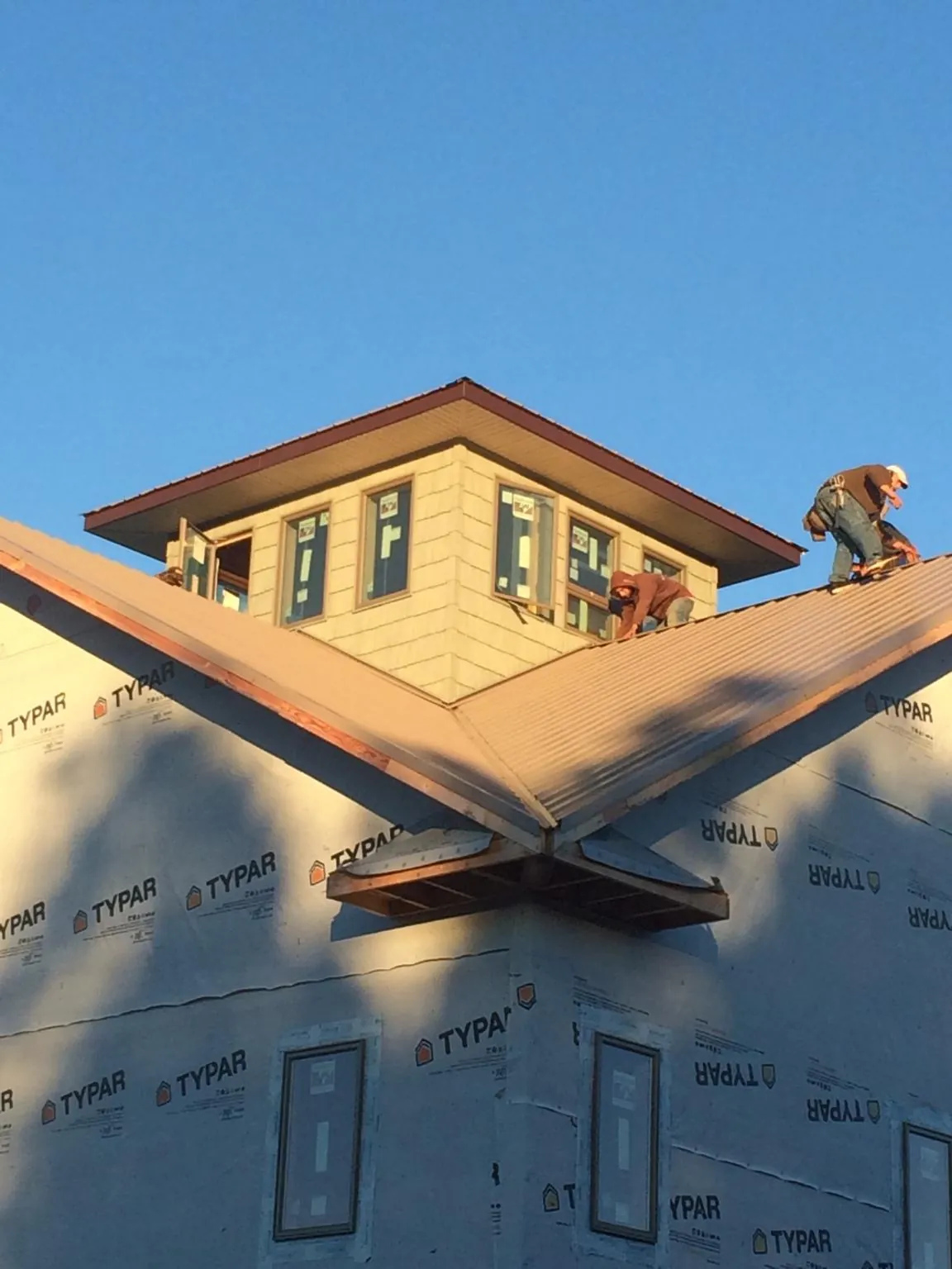 Roofers working around a rooftop cupola on a new metal roof at sunset — Roof Waterproofing in Cave Creek by Roofing Brothers